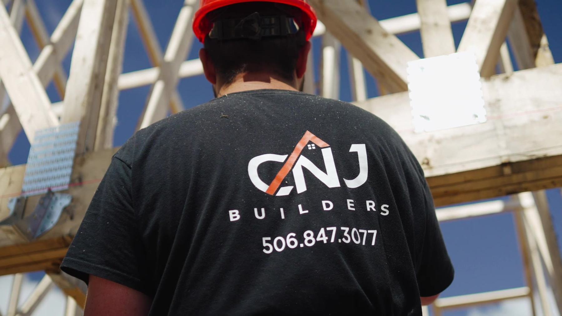 CNJ Builders crew member in a company shirt working on roof trusses